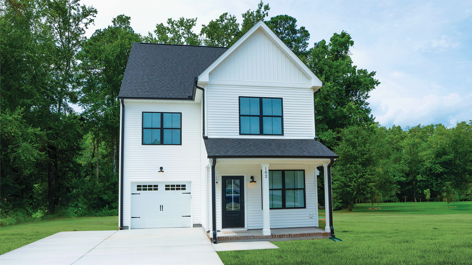 Move-In Ready Homes. Suffolk Johnson Home. The Johnson Exterior Front White with Black Windows, Porch, Garage, Driveway, and Grass